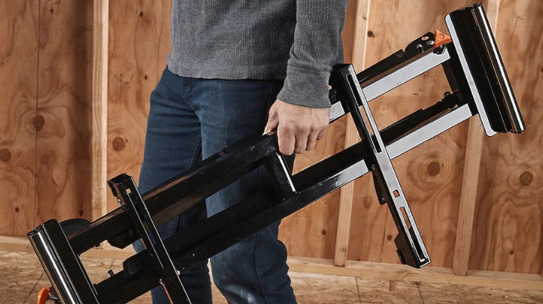 Close-up of a man holding Warrior's 350 pound Folding Miter Saw Stand