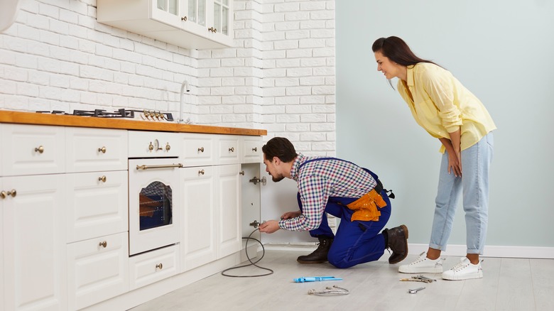 Two people fixing kitchen sink