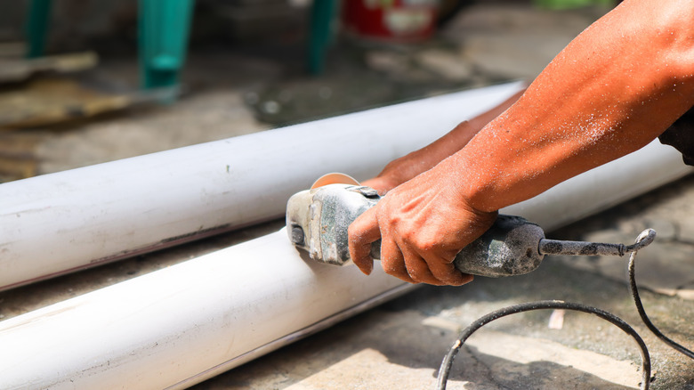 Person cutting a PVC pipe with a saw