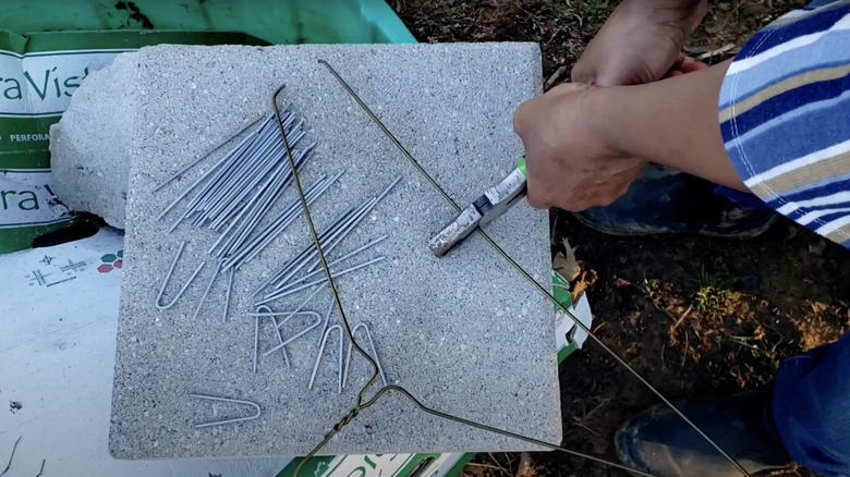 A person uses wire cutters to cut the bar of a wire coat hanger into smaller pieces.