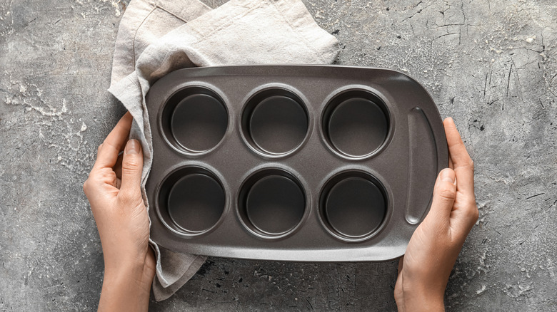 A person holds a clean muffin tin over a countertop