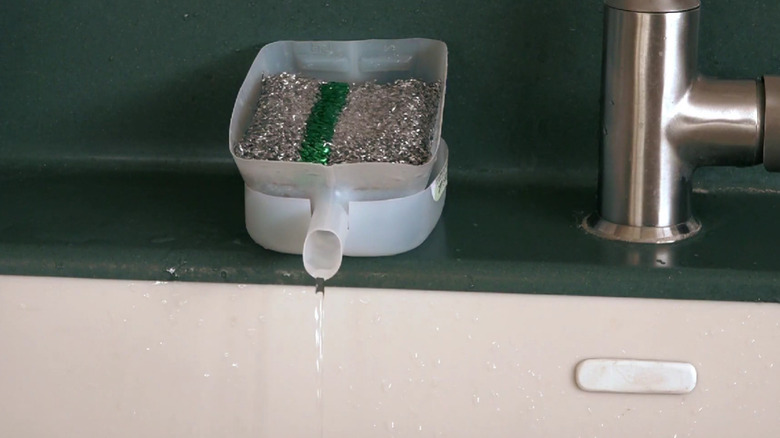 A plastic sponge holder with a spout made from a yogurt carton.