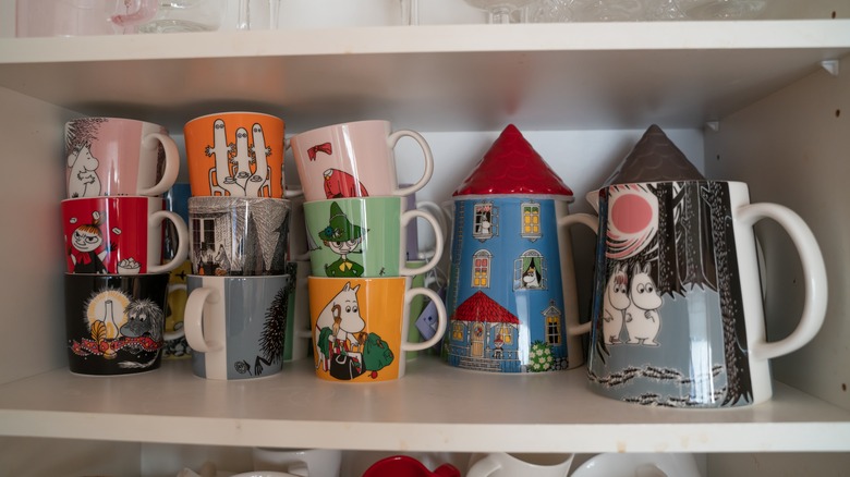Collection of colorful mugs on open shelf