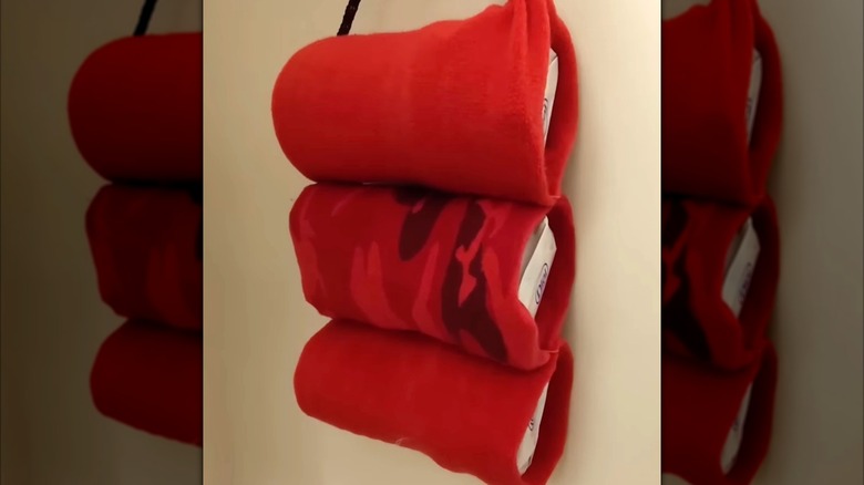 DIY bathroom wall storage made from plastic water bottles wrapped in red fabric