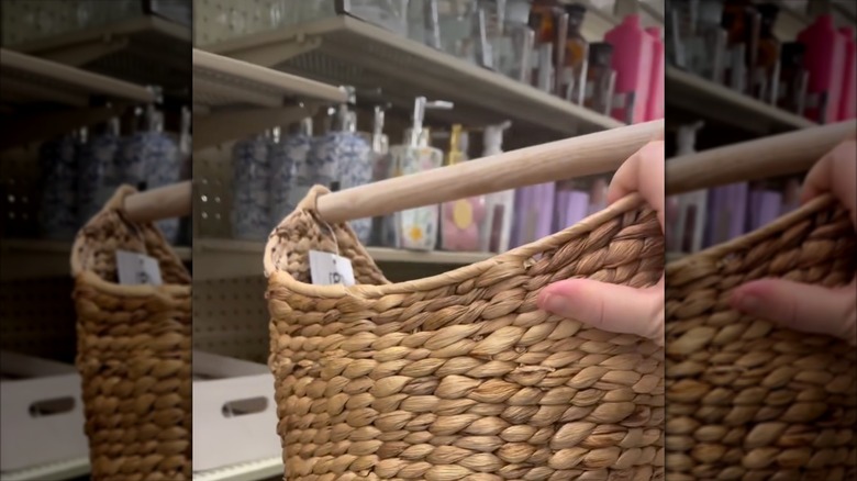 A person takes a Hobby Lobby woven basket with a wooden handle from the store shelf.
