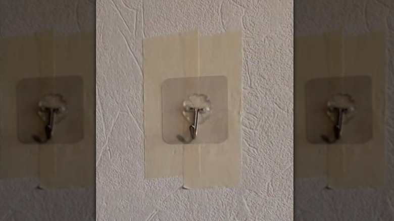 adhesive hook with painters tape on wall