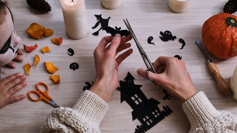 Closeup of person's hands cutting out decorations for halloween