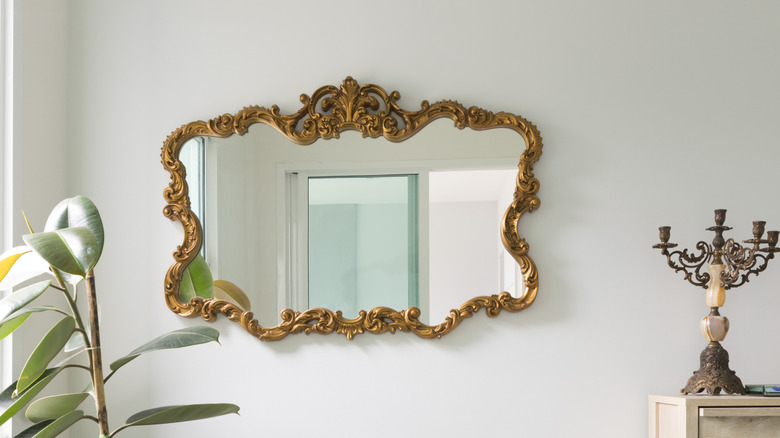 Vintage mirror with gold ornate on white wall