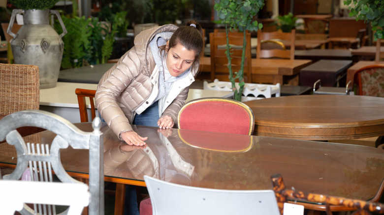 A woman inspecting a dining table in a secondhand store