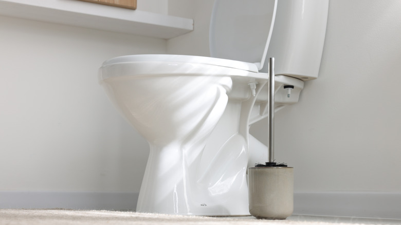 Toilet and toilet brush in white bathroom