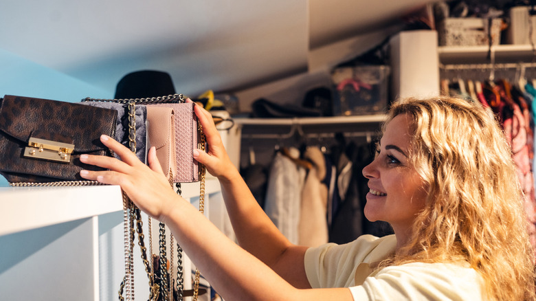 Woman trying to organize purses in her closet
