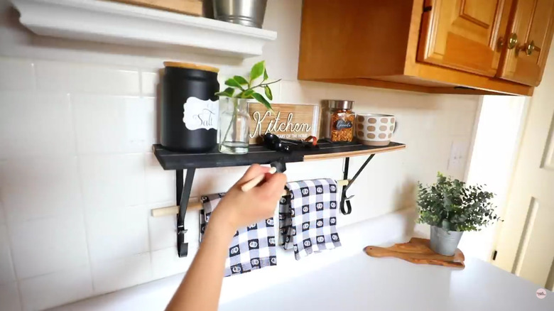 A hand staining a shelf made from Dollar Tree items
