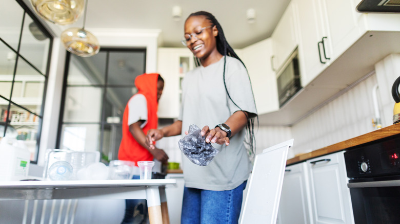 Woman tossing an item into the kitchen trash