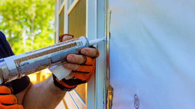 A person caulking around a window