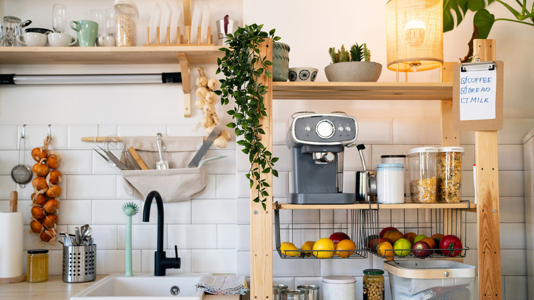 Kitchen sink next to wood shelving unit for coffee machine and storage