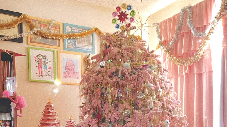 A pink flocked Christmas tree with gold tinsel and colorful ornaments