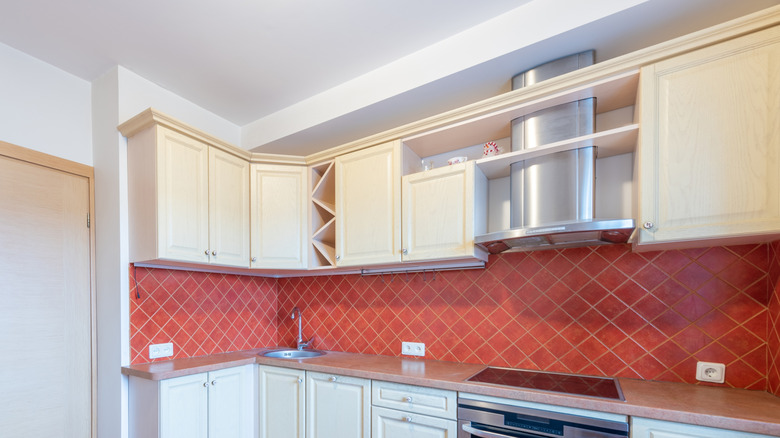 Kitchen with white cabinets and red backsplash with pink grout