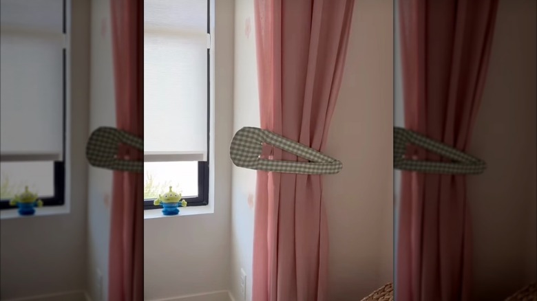 A giant gingham-patterned snap barrette used as a tieback for a pink curtain panel.