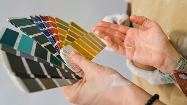 Hands of painters holding a variety of different paint swatches