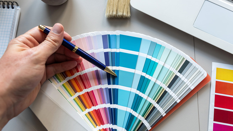 A hand pointing to colors on a color swatch sample with a pen