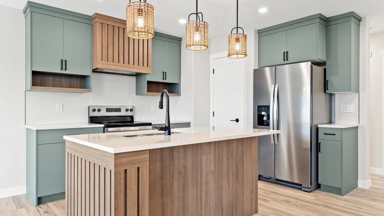 Kitchen with a stainless steel refrigerator, green cabinets, and a wood island