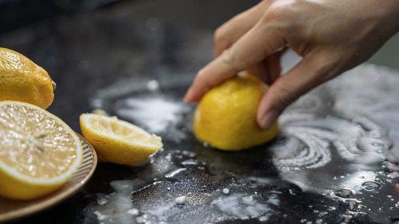 Person using baking soda and lemon to clean a baking sheet