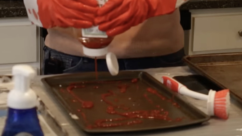 Person pouring ketchup on burnt baking sheet