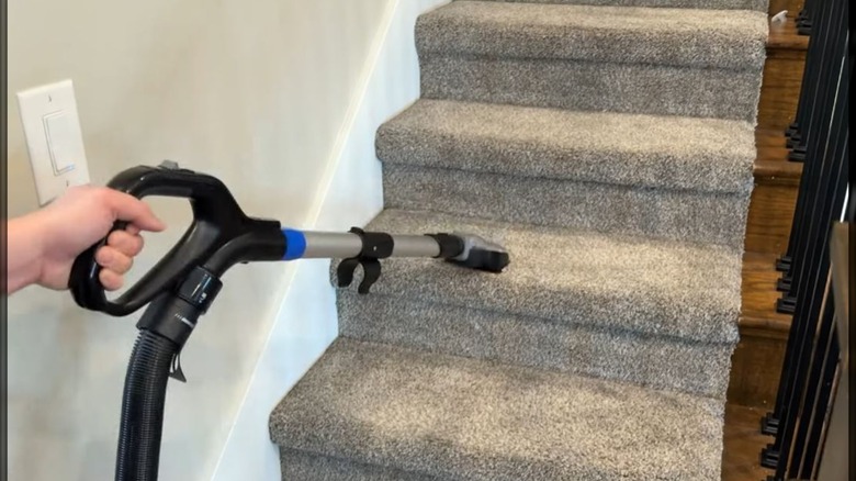 person using bissell handheld attachment on stairs