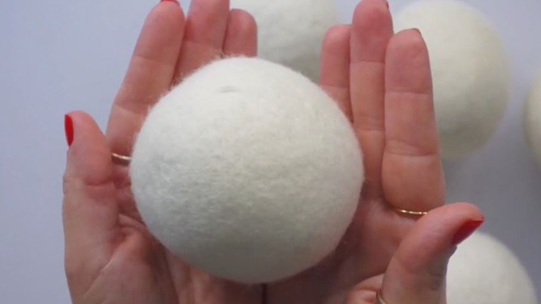closeup of person holding Handy Laundry wool dryer ball with more in background
