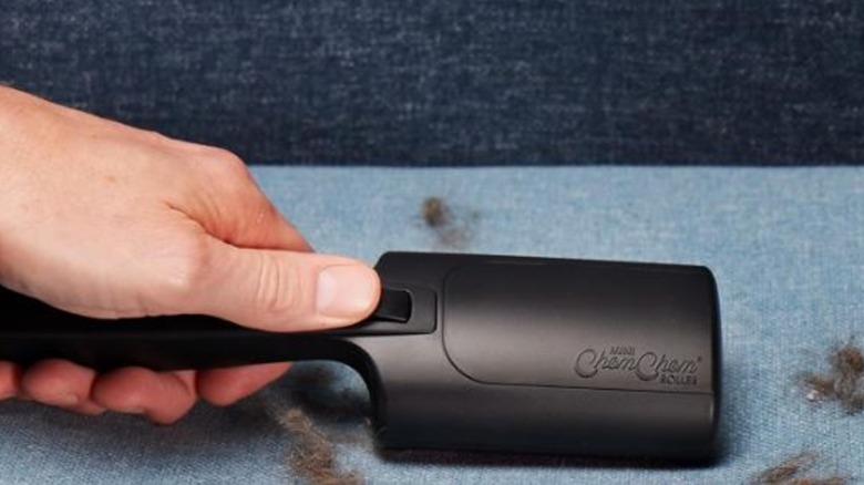 close-up of person using Mini ChomChom roller on furry couch