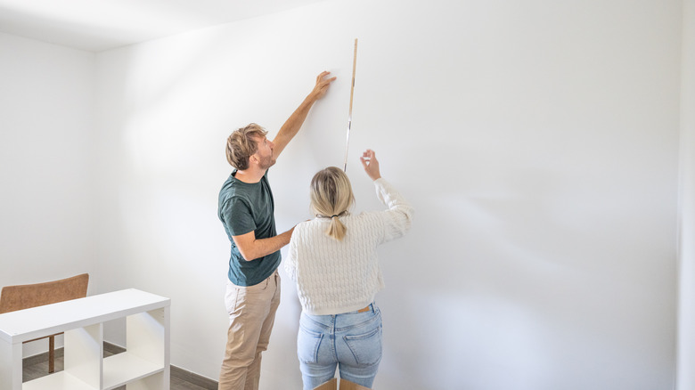 A couple taking measurements of a wall