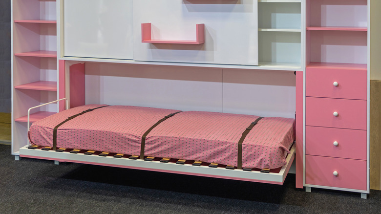 Murphy bed unfolded with pink drawers around it