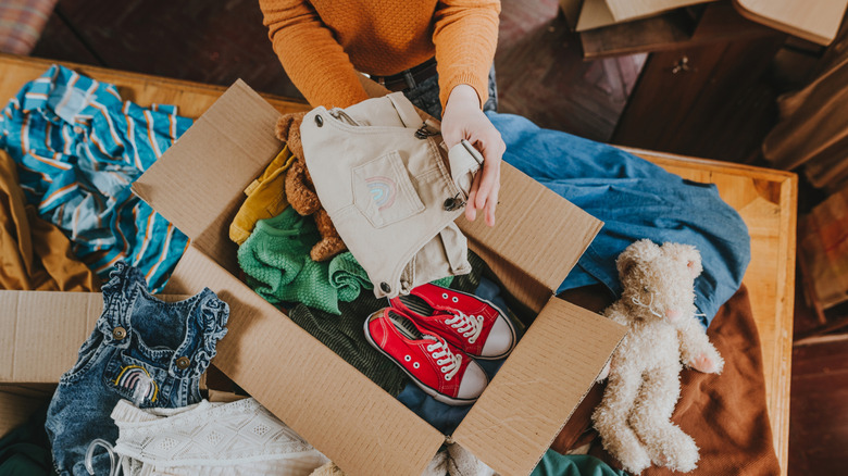 Person packing children's toys and clothes into a cardboard box