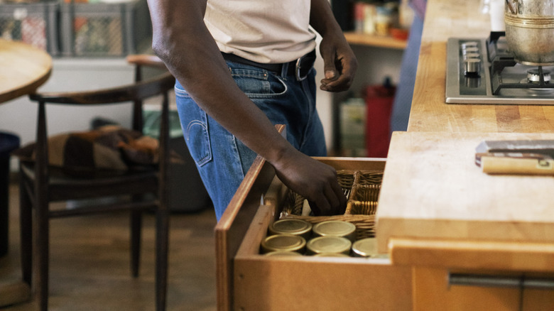 Man in the kitchen reaching into a kitchen drawer