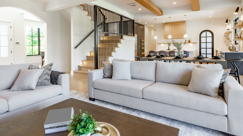 wood coffee table between sofa and love seat with books on top