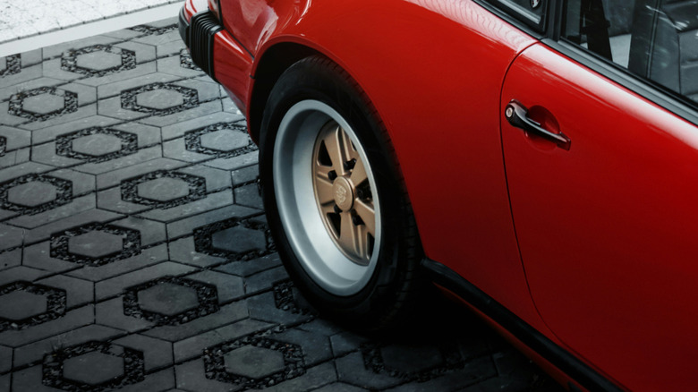 A red car parked on rubber tile driveway.