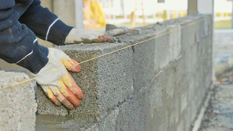 A construction worker building concrete brick wall