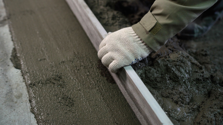 A worker leveling the edge of a driveway