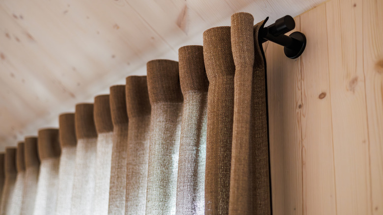 Brown linen curtains in a room with wood paneled walls and ceiling