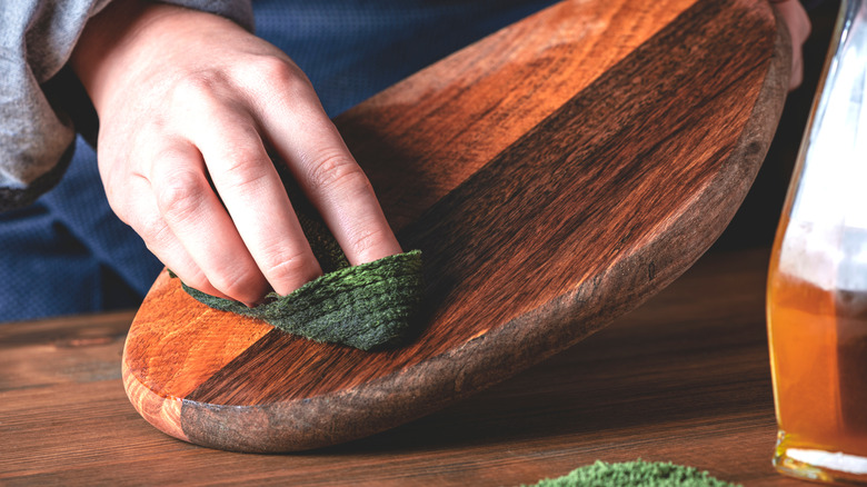 Close up of woman adding wax to a small wooden cutting board