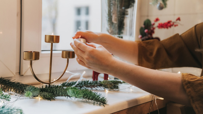Close-up of a person lighting a candle near a window