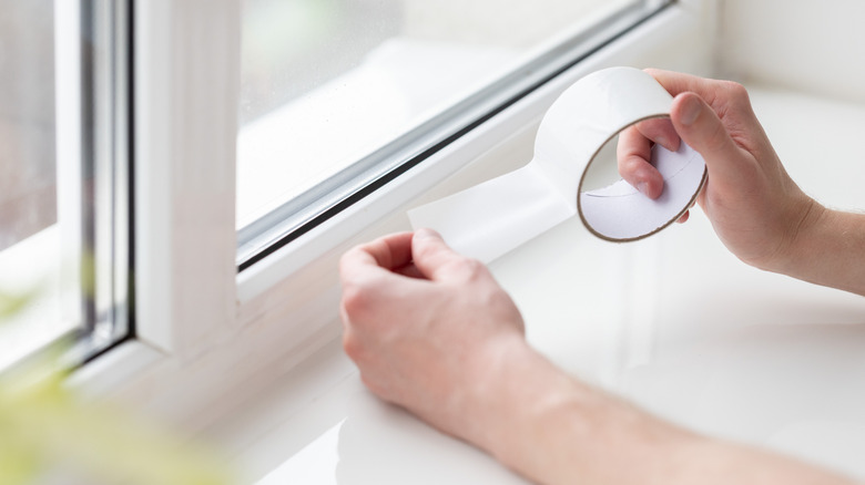 Close up of a person applying draft tape around a window