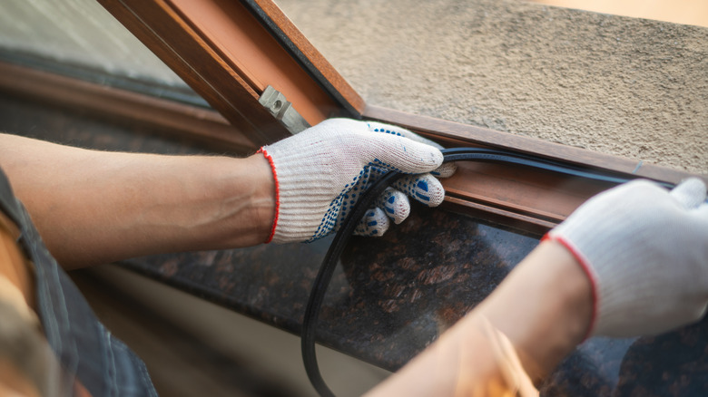 Close-up of a person applying new weatherstripping to a window
