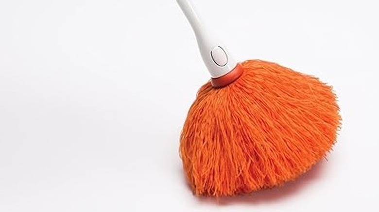 An orange duster with thin orange fibers and a white handle