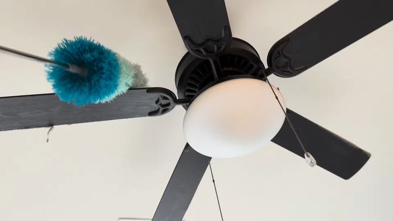 Using a colorful bendable duster to clean a fan's blades
