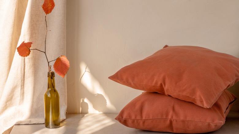 Photo of terracotta colored pillows next to bone white wall