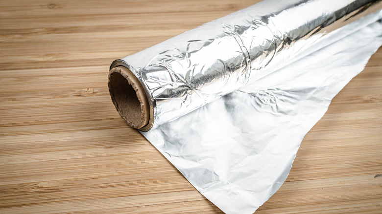 Rolled up aluminum foil on a rustic wooden table.