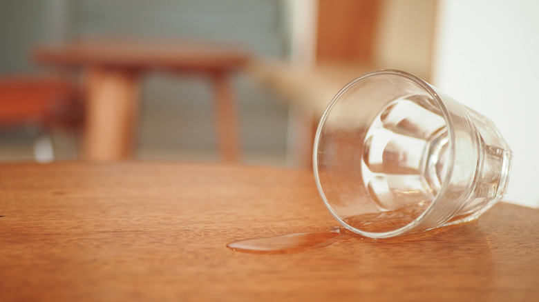 A glass that's been knocked over sitting on a wood table