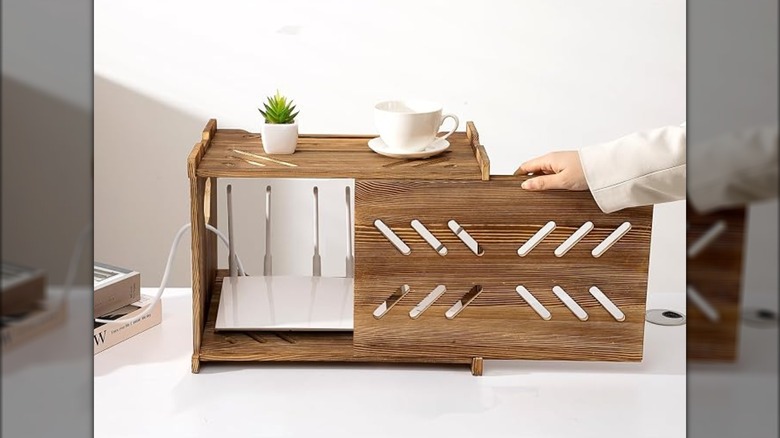 A hand slides open the door of the CABTE storage box, revealing the Wi-Fi router inside