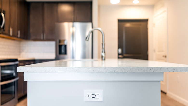 White kitchen island with an outlet on the side